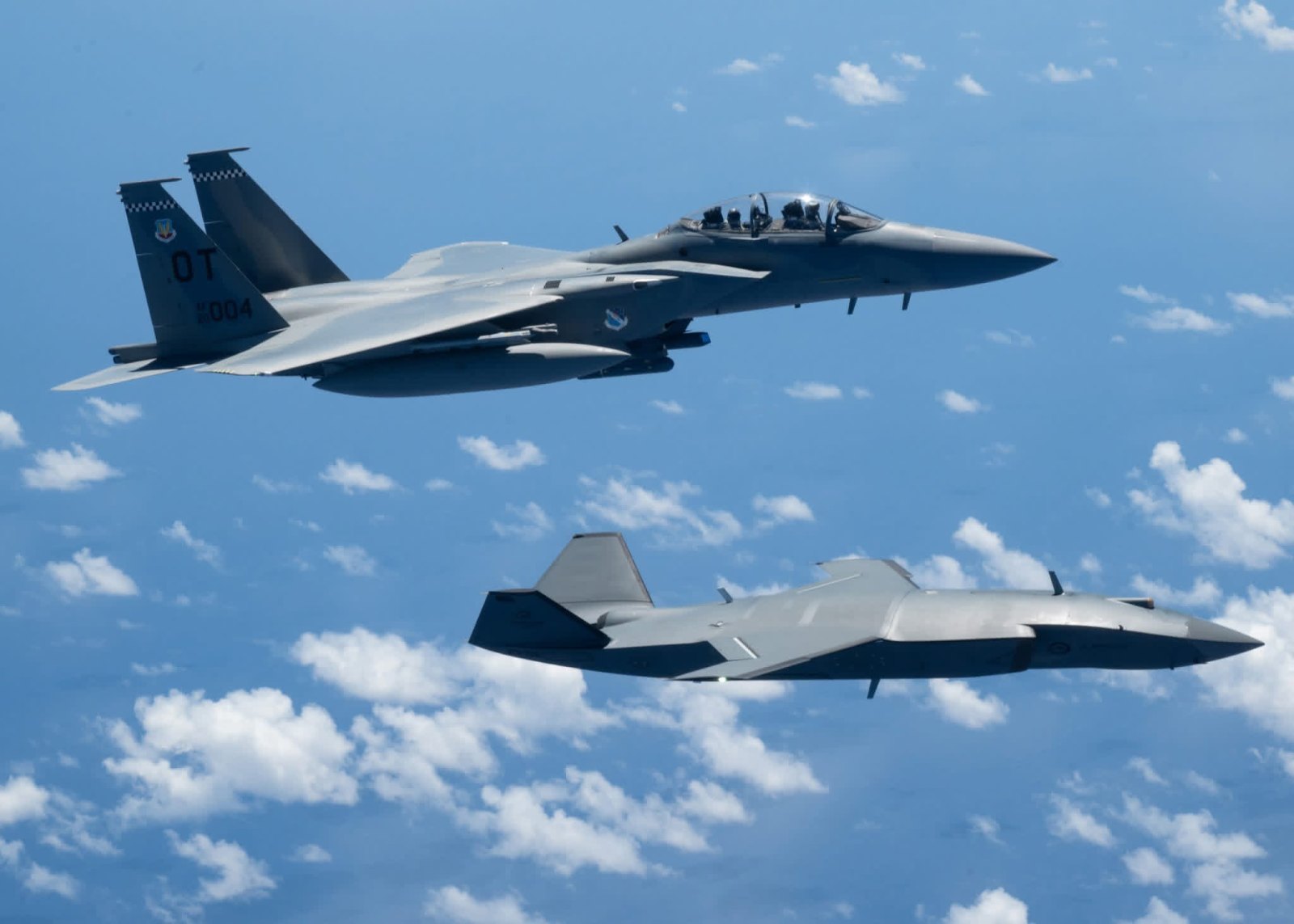 Bir MQ-28 Ghost Bat, Valiant Shield 2026 tatbikatında ABD Hava Kuvvetleri'ne ait F-15EX Eagle II ile birlikte Filipin Denizi üzerinde uçuyor.